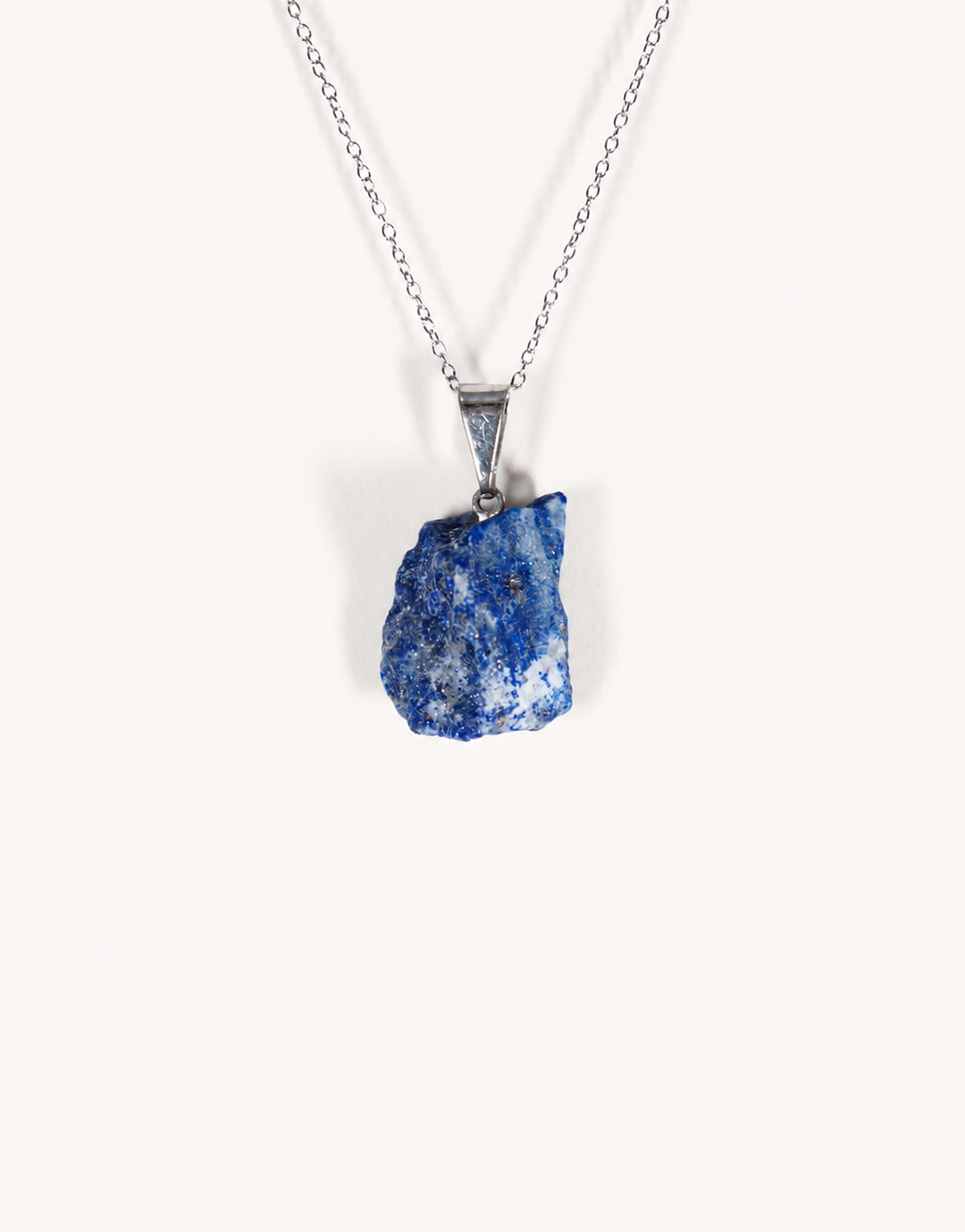 A Natural Raw Lapis Lazuli Pendant featuring an unpolished deep blue stone with golden pyrite flecks on an 18-inch stainless steel chain.