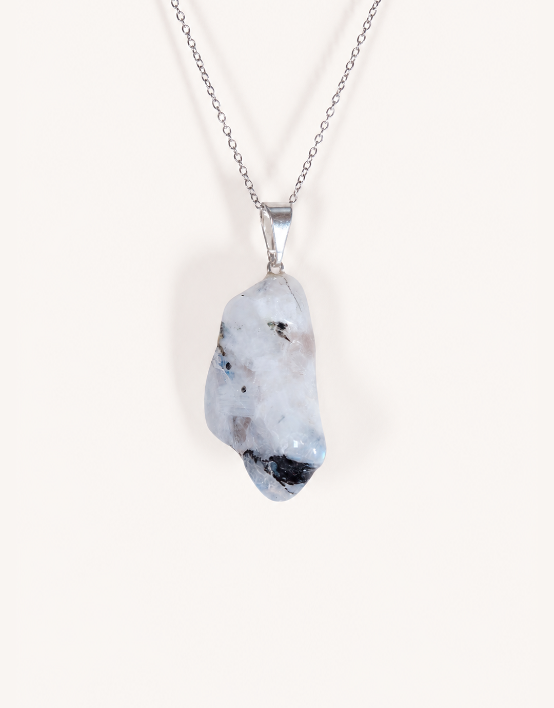 A freeform Natural Moonstone Pendant featuring opaque white stone with black tourmaline matrix spots on an 18-inch stainless steel chain.