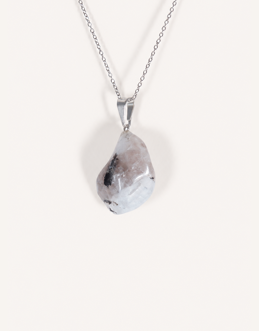 A freeform Natural Moonstone Pendant featuring opaque white stone with black tourmaline matrix spots on an 18-inch stainless steel chain.