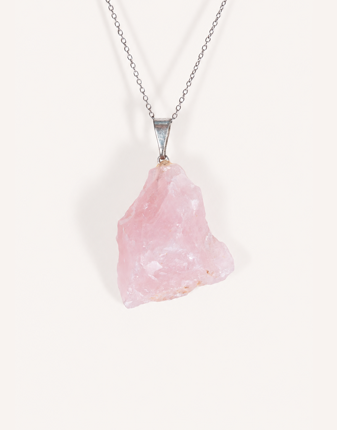 Natural raw rose quartz pendant showcasing rough blush-pink crystal texture on a complimentary 18-inch stainless steel chain.
