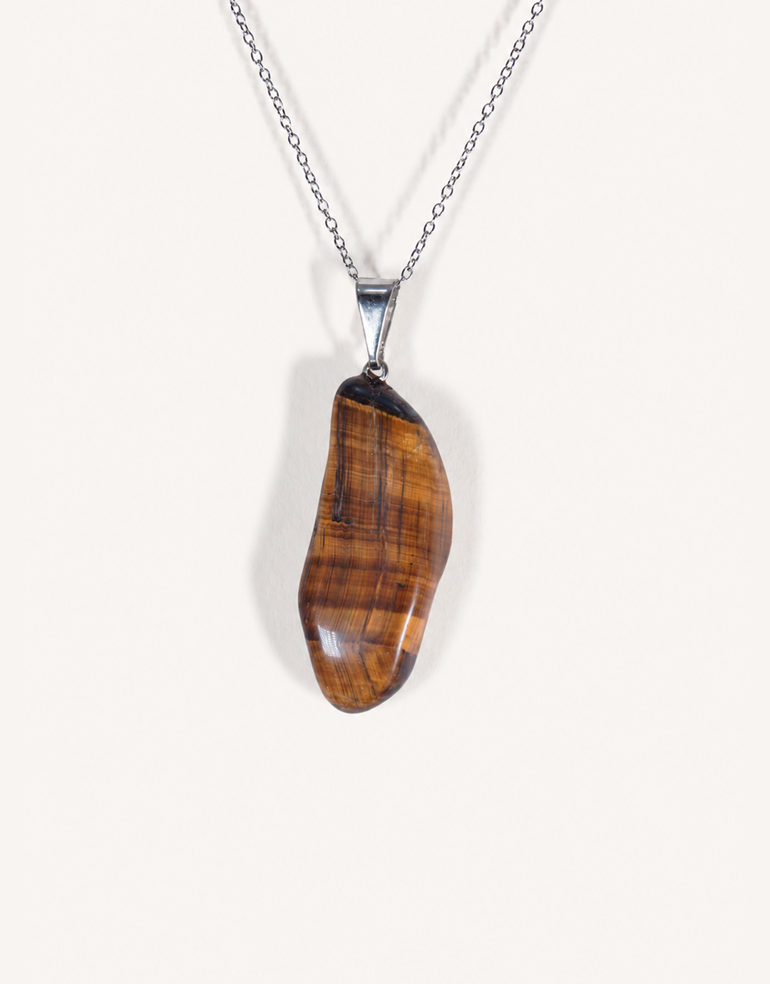 A Natural Freeform Tiger's Eye Pendant in a unique organic shape displaying golden-brown chatoyant shimmer on an 18-inch stainless steel chain.