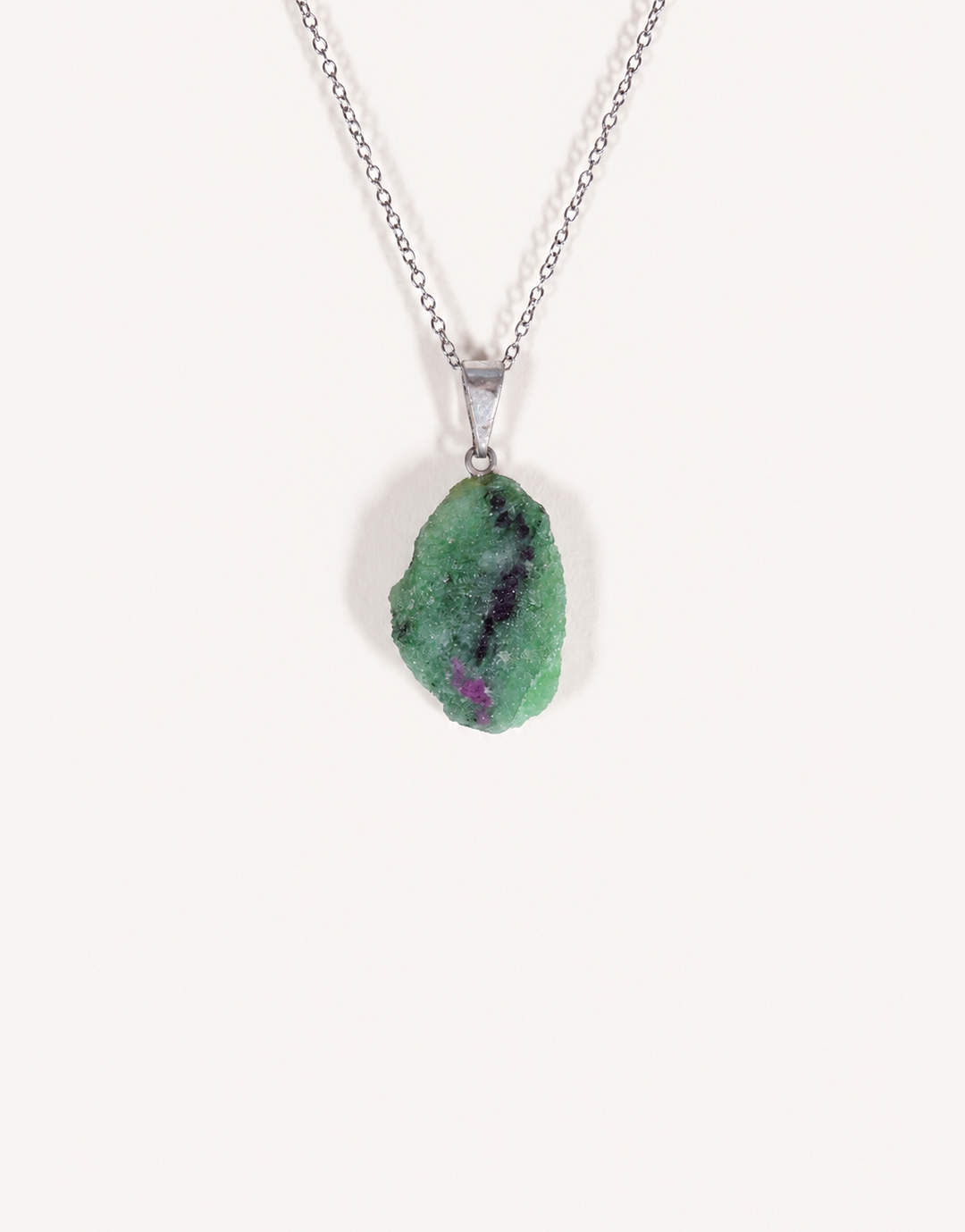 A Natural Raw Zoisite Pendant featuring a rough green crystal stone with black inclusions and a magenta ruby matrix spot on an 18-inch stainless steel chain.