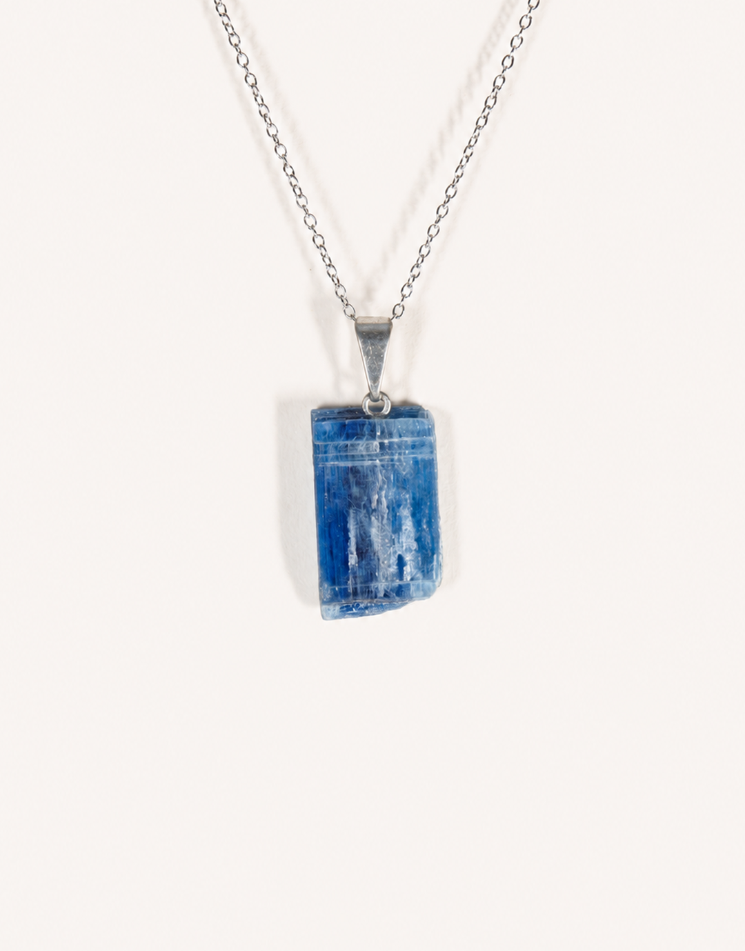 A Natural Kyanite Pendant in deep denim blue hanging from an 18-inch stainless steel chain.