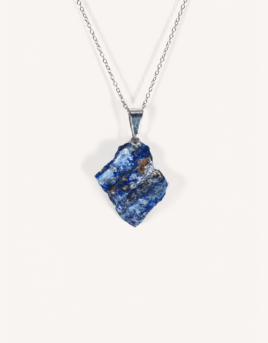 A Natural Raw Lapis Lazuli Pendant featuring an unpolished deep blue stone with golden pyrite flecks on an 18-inch stainless steel chain.