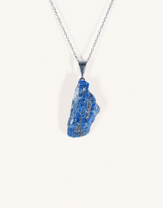 A Natural Raw Lapis Lazuli Pendant featuring an unpolished deep blue stone with golden pyrite flecks on an 18-inch stainless steel chain.