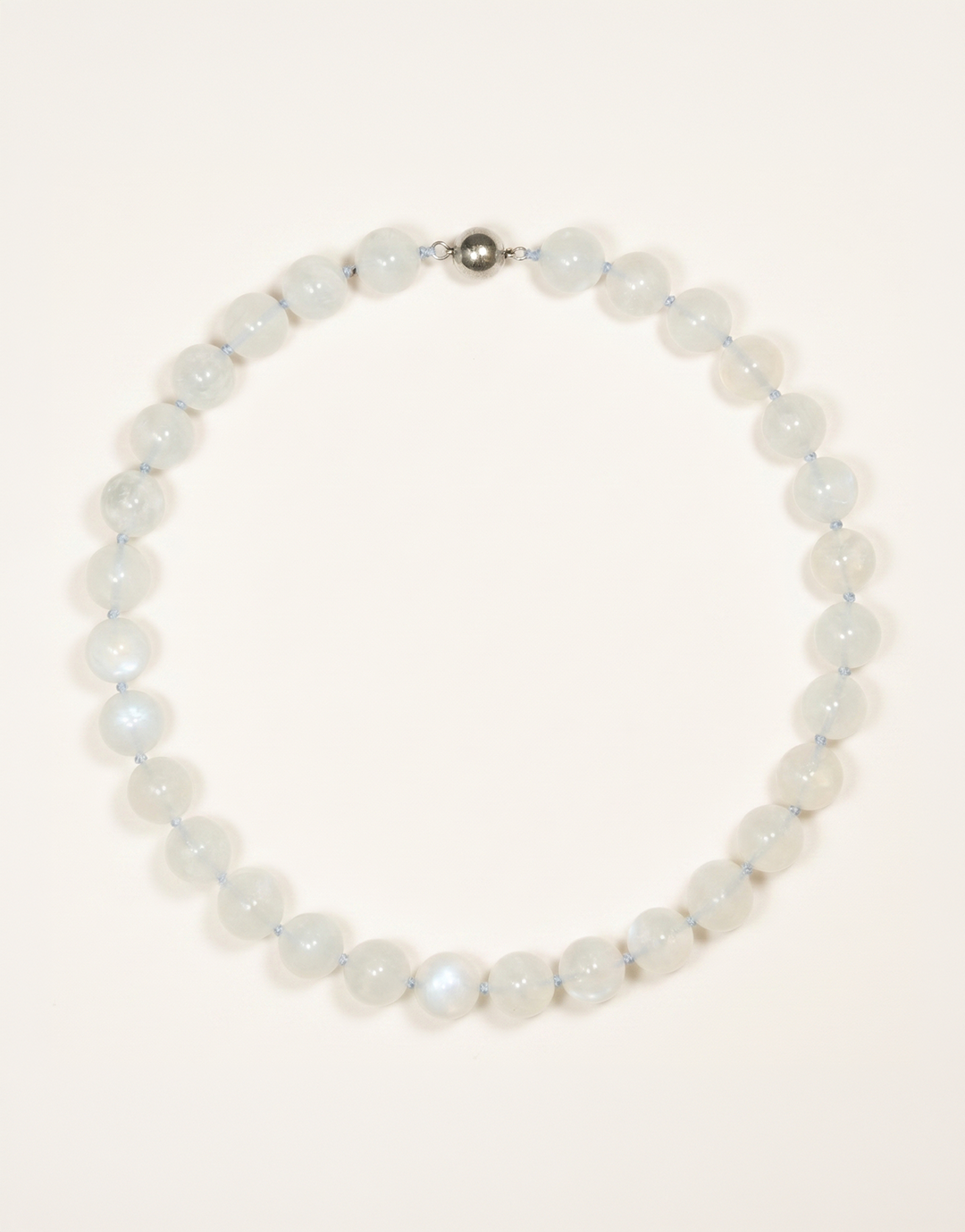 A 16-inch Natural Moonstone Choker showcasing smooth 12mm milky white beads with a soft floating blue flash.