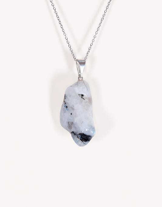 A freeform Natural Moonstone Pendant featuring opaque white stone with black tourmaline matrix spots on an 18-inch stainless steel chain.