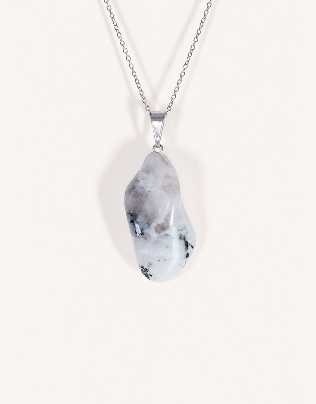 A freeform Natural Moonstone Pendant featuring opaque white stone with black tourmaline matrix spots on an 18-inch stainless steel chain.