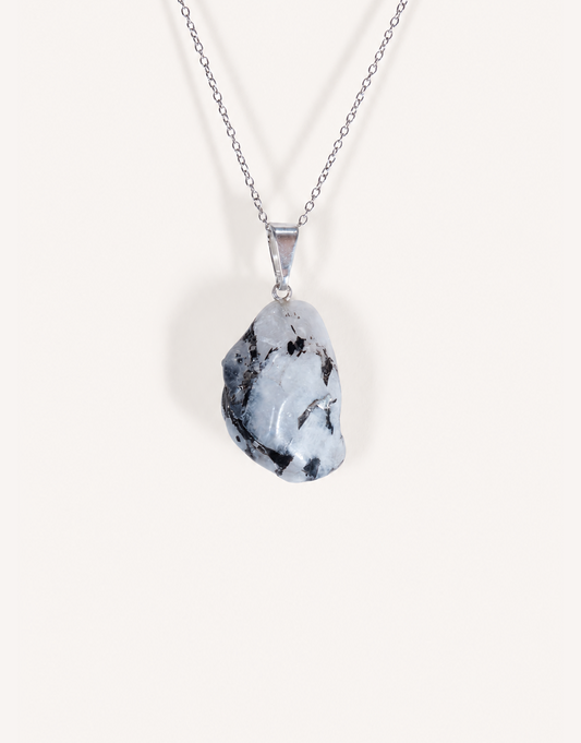 A freeform Natural Moonstone Pendant featuring opaque white stone with black tourmaline matrix spots on an 18-inch stainless steel chain.