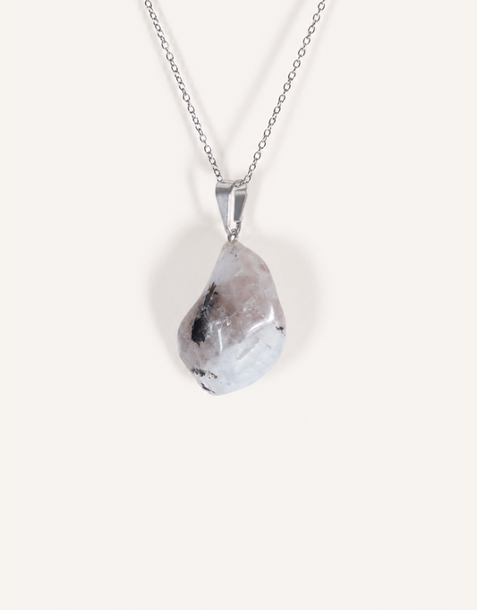A freeform Natural Moonstone Pendant featuring opaque white stone with black tourmaline matrix spots on an 18-inch stainless steel chain.