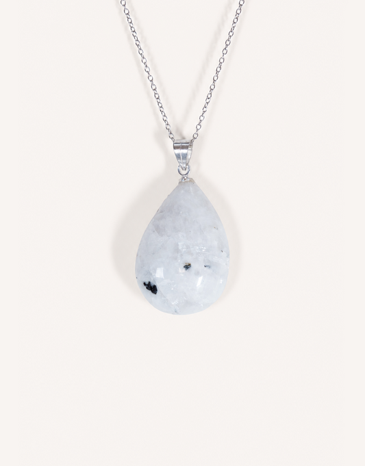 A freeform Natural Moonstone Pendant featuring opaque white stone with black tourmaline inclusions on an 18-inch stainless steel chain.