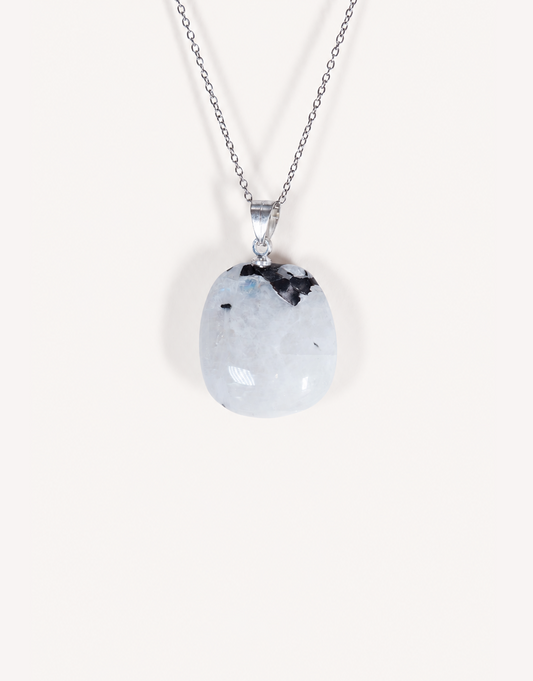 A freeform Natural Moonstone Pendant featuring opaque white stone with black tourmaline inclusions on an 18-inch stainless steel chain.