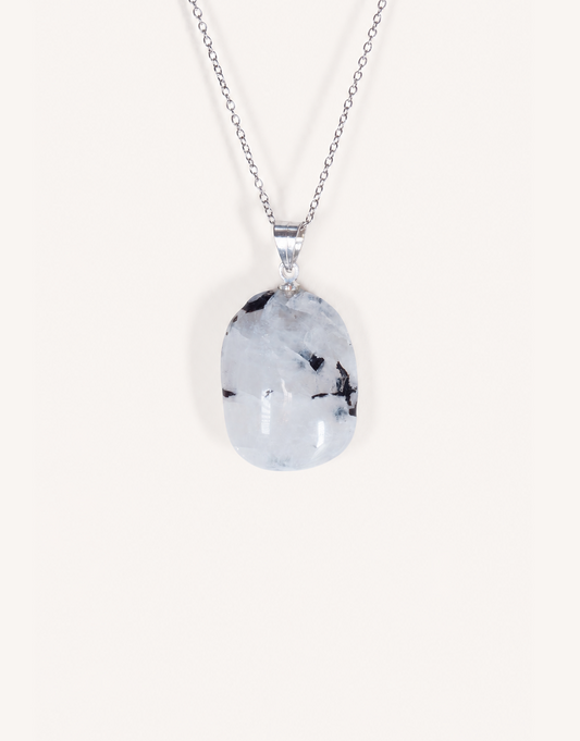A freeform Natural Moonstone Pendant featuring opaque white stone with black tourmaline inclusions on an 18-inch stainless steel chain.