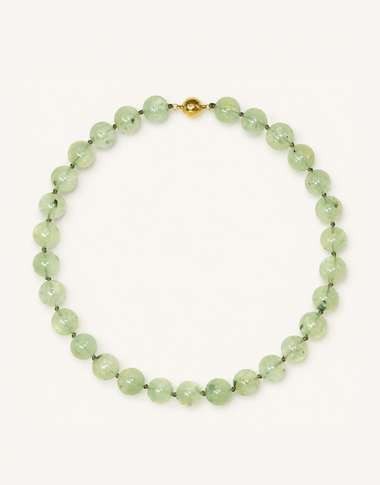 A 16-inch Natural Prehnite Choker featuring polished 12mm light green beads with unique dark tourmaline inclusions.