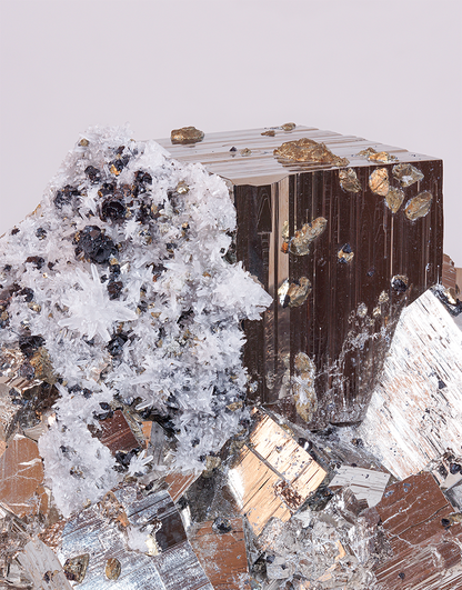 A lustrous cubic Pyrite mineral specimen with white quartz needles, chalcopyrite, and dark sphalerite inclusions from Huanzala Mine, Peru, measuring 9 x 13 cm.