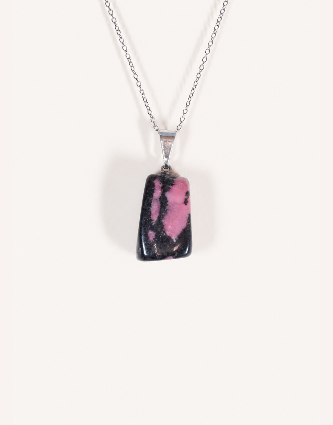 A Natural Rhodonite Pendant featuring a smooth dusty-rose stone with black manganese matrix veins on an 18-inch stainless steel chain.