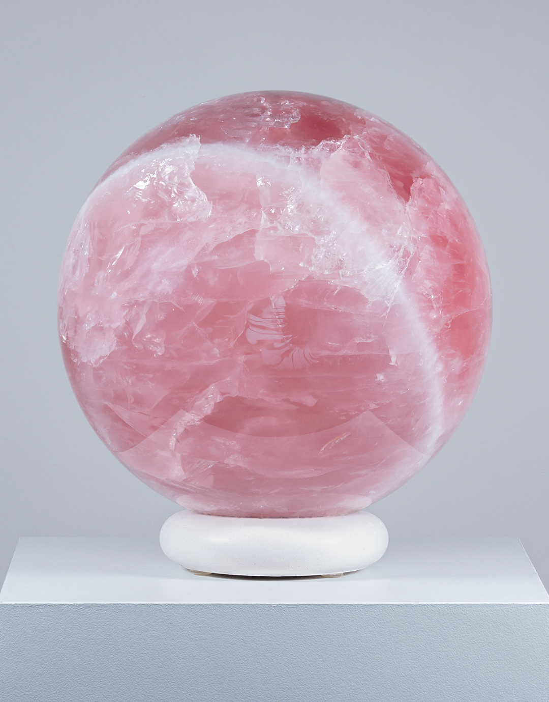 A large 6.3 kg Natural Rose Quartz Sphere from Brazil in deep blush pink, resting on a white display stand.
