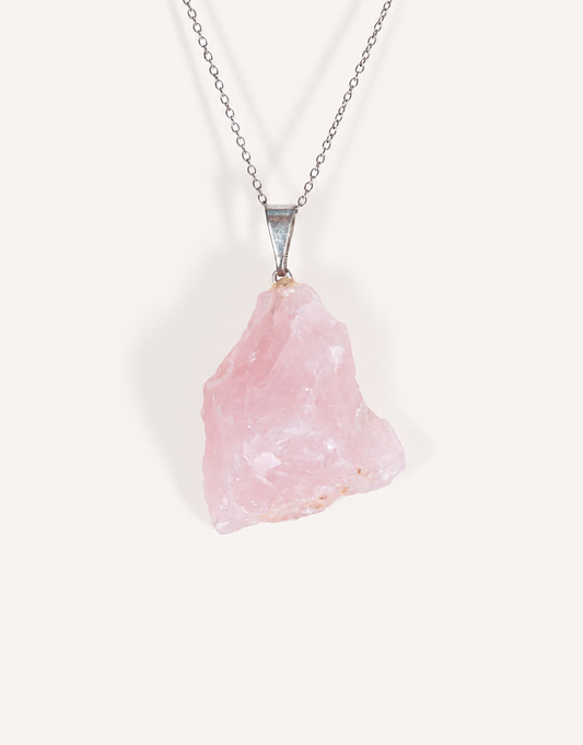 Natural raw rose quartz pendant showcasing rough blush-pink crystal texture on a complimentary 18-inch stainless steel chain.