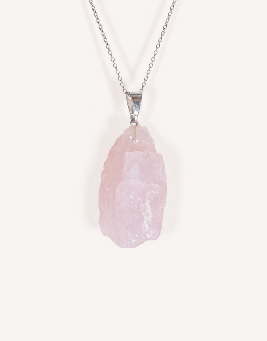 Natural raw rose quartz pendant showcasing rough blush-pink crystal texture on a complimentary 18-inch stainless steel chain.