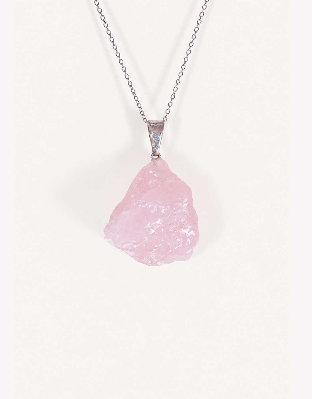 Natural raw rose quartz pendant showcasing rough blush-pink crystal texture on a complimentary 18-inch stainless steel chain.