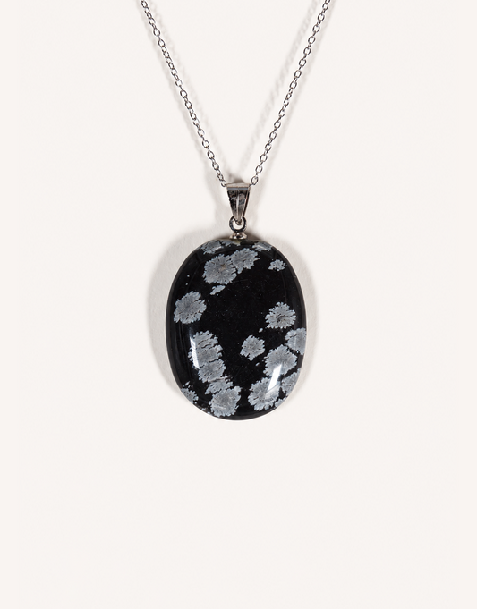 A Natural Snowflake Obsidian Pendant displaying smooth black stone with white cristobalite patches on an 18-inch stainless steel chain.