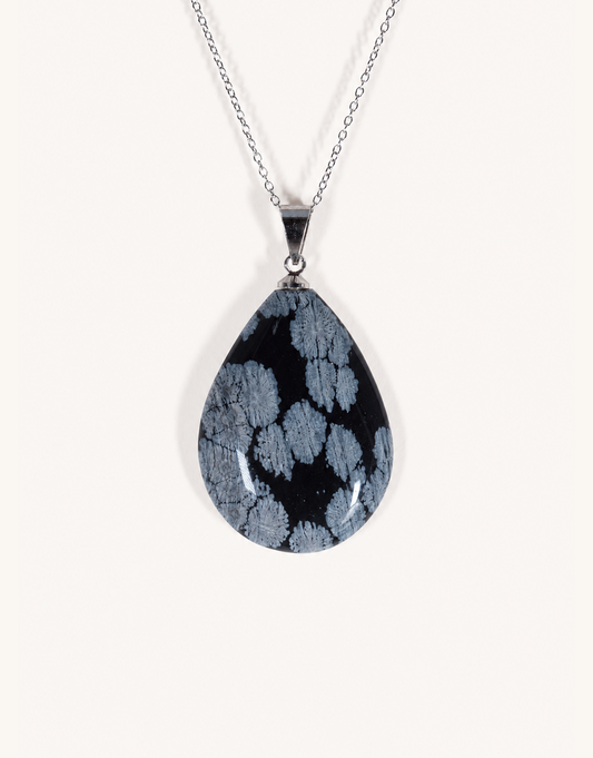 A Natural Snowflake Obsidian Pendant displaying smooth black stone with white cristobalite patches on an 18-inch stainless steel chain.