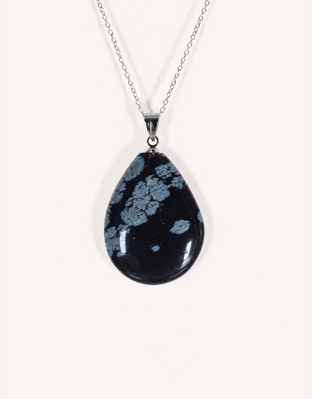 A Natural Snowflake Obsidian Pendant displaying smooth black stone with white cristobalite patches on an 18-inch stainless steel chain.
